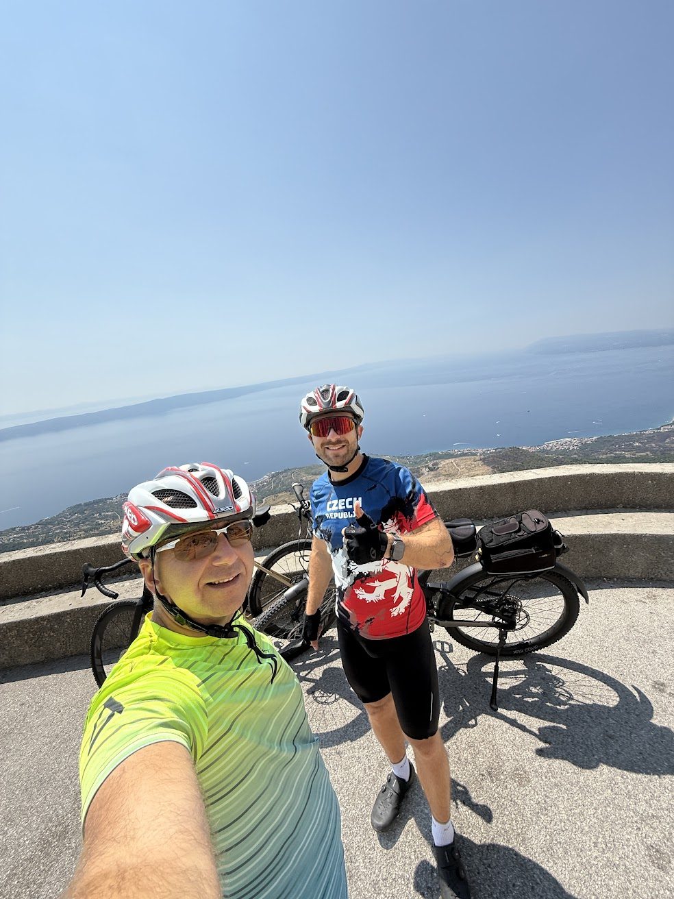 Dvaja cyklisti s bicyklami na vyhliadke nad pobrežím
