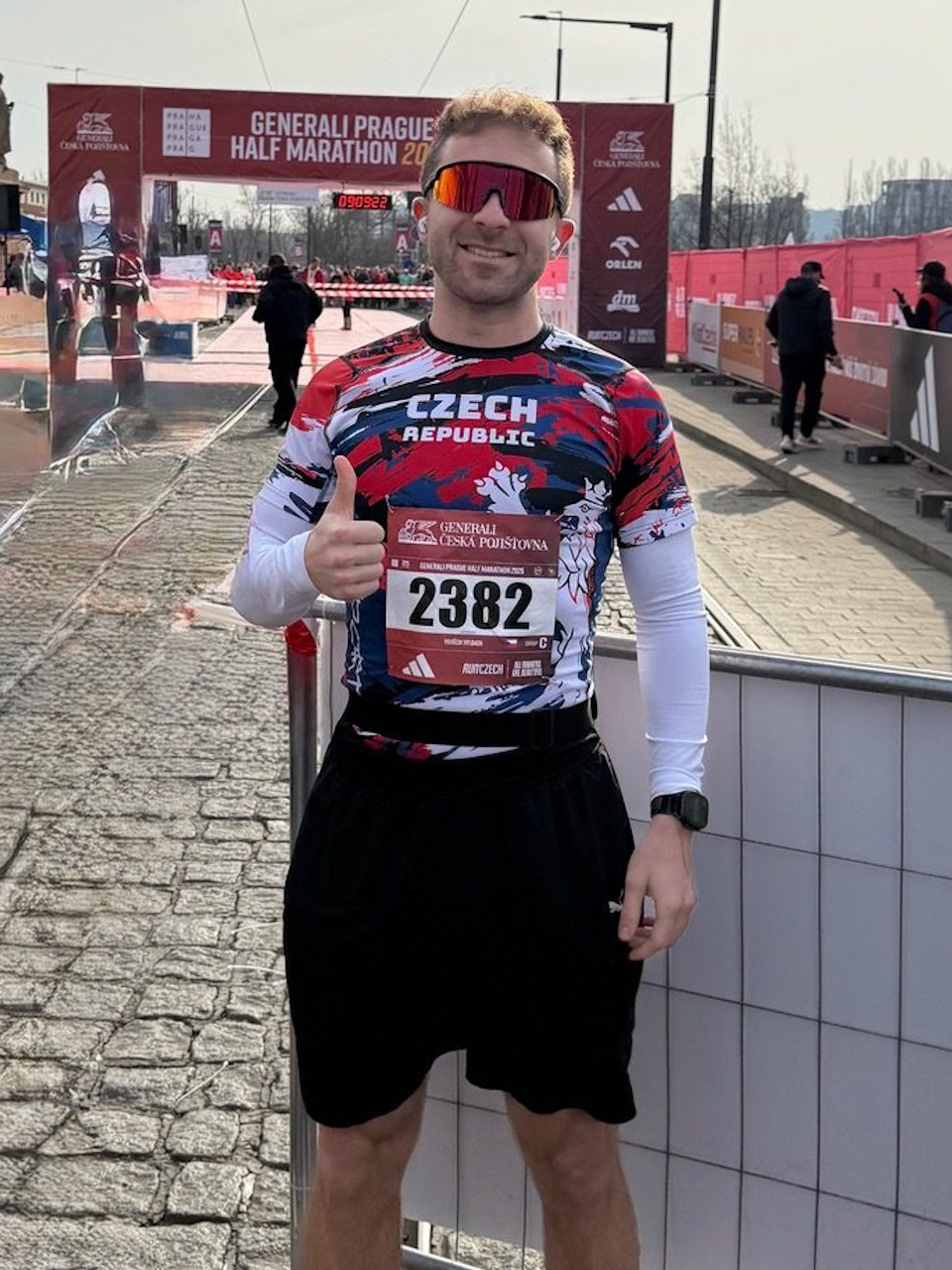 Bežec so štartovným číslom a športovými okuliarmi pred cieľovým priestorom závodu
