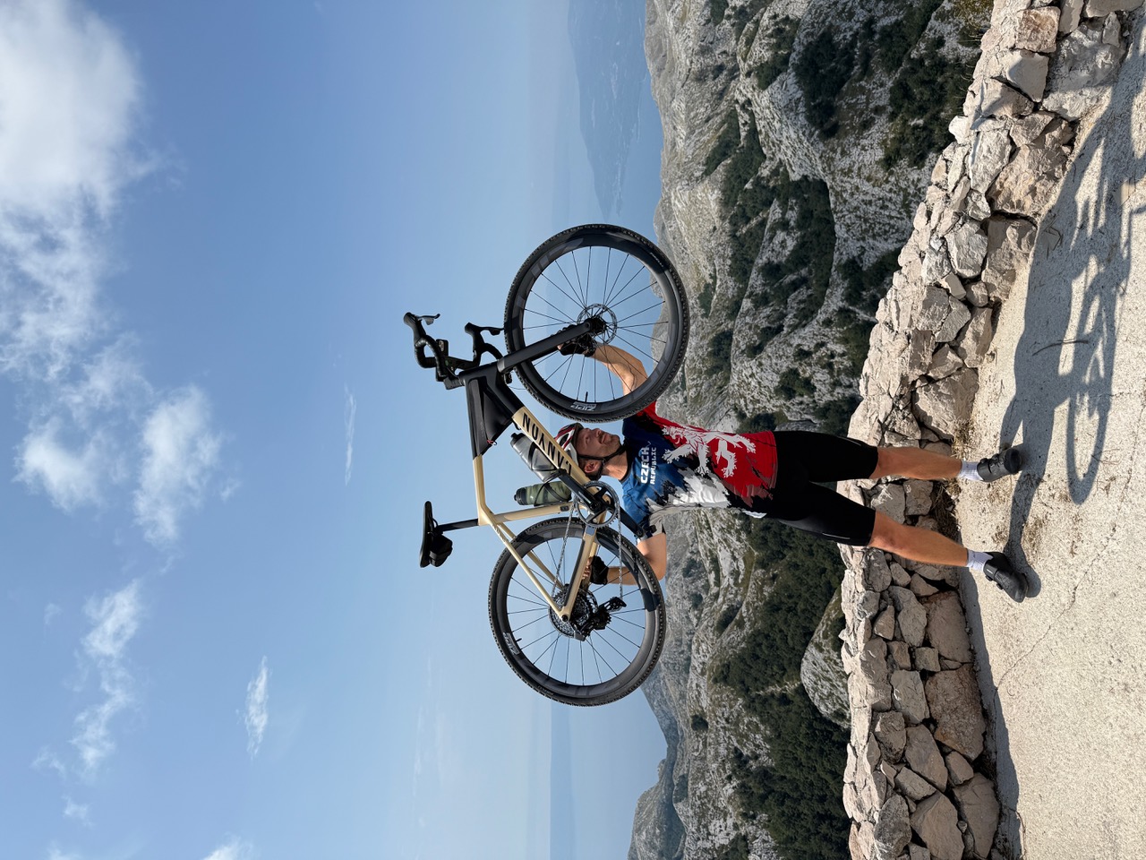 Cyklista drží bicykel na vyhliadke nad hornatou krajinou